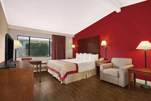 um quarto de hotel com uma cama e uma televisão em Ramada by Wyndham Torrance em Torrance