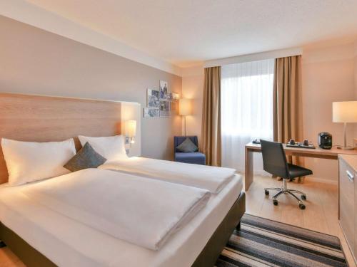 a hotel room with a large bed and a desk at Mercure Aachen Europaplatz in Aachen