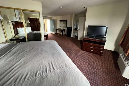 a hotel room with a bed and a flat screen tv at Days Inn & Suites by Wyndham Rancho Cordova in Rancho Cordova