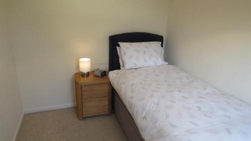 a small bedroom with a bed and a lamp on a nightstand at Templecombe in Temple Combe