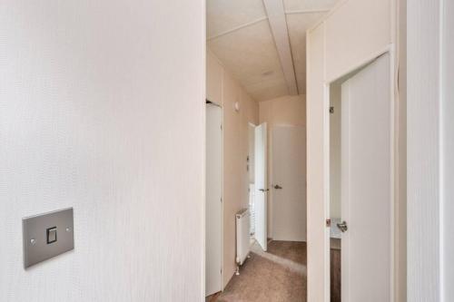 a hallway with white walls and an open door at Spacious Stunning Lakeside 3 bed Holiday Home in Northampton