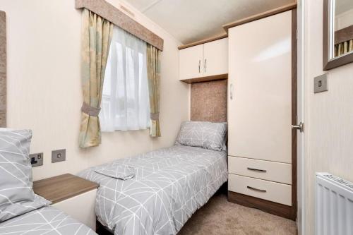 um pequeno quarto com uma cama e uma janela em Spacious Stunning Lakeside 3 bed Holiday Home em Northampton