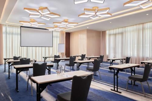 a conference room with tables and chairs and a projection screen at Radisson Blu Hotel Riyadh Convention and Exhibition Center in Riyadh