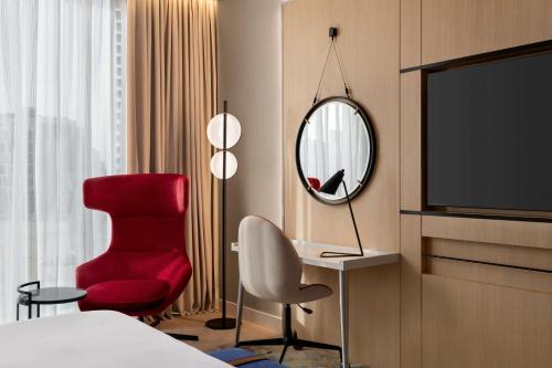 a hotel room with a red chair and a mirror at Radisson Blu Hotel Riyadh Convention and Exhibition Center in Riyadh