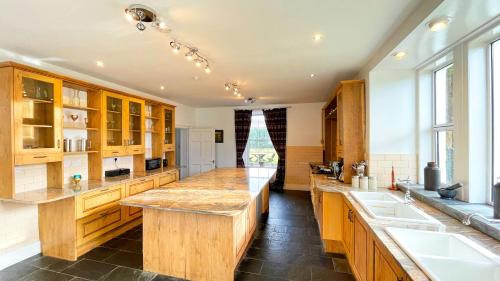 una gran cocina con armarios de madera y una gran isla en Pentland Farm House en Kirknewton