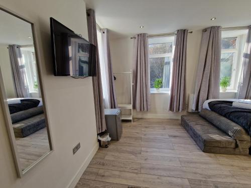 a bedroom with a mirror and a bed and a couch at Flat 1, Modern studio apartment, Tynte Hotel, Mountain Ash in Quakers Yard