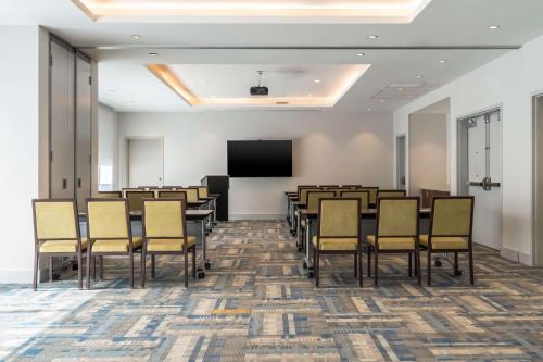 a conference room with tables and chairs and a screen at Hyatt Place Gainesville Downtown in Gainesville