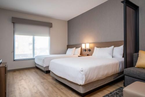 a hotel room with two beds and a couch at Hyatt Place Gainesville Downtown in Gainesville