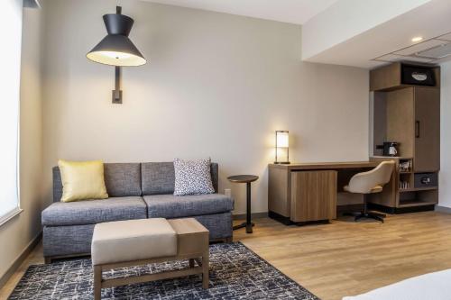 a living room with a couch and a desk at Hyatt Place Gainesville Downtown in Gainesville