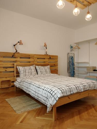 a bedroom with a large bed with a wooden headboard at B Apartments - Babel Apartment in Timişoara