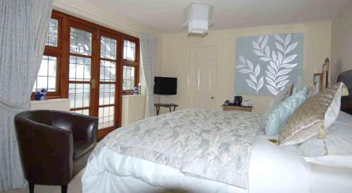 a bedroom with a white bed and a chair at Cleavers Lyng 16th Century Country House in Herstmonceux