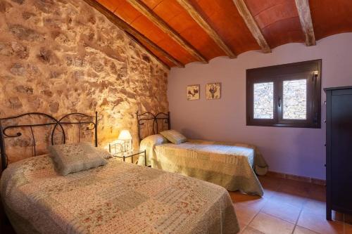 a bedroom with two beds and a stone wall at Cal Sec in Mas Boquera