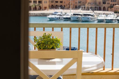 a table with a plant on a balcony with boats in the water at El Gouna Elite Worldwide Sea & Garden Residences - Hurghada, Egypt in Hurghada