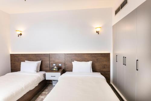 two beds in a room with white walls and wood at El Gouna Elite Worldwide Sea & Garden Residences - Hurghada, Egypt in Hurghada