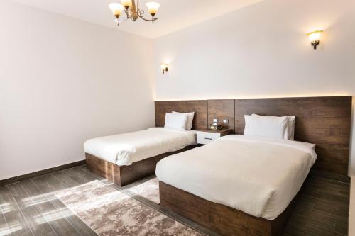 two beds in a hotel room with white sheets at El Gouna Elite Worldwide Sea & Garden Residences - Hurghada, Egypt in Hurghada