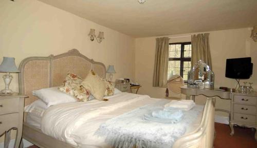 a bedroom with a bed and a desk and a television at Cleavers Lyng 16th Century Country House in Herstmonceux