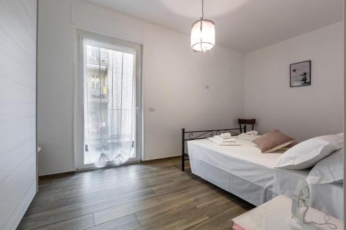 Habitación blanca con cama y ventana en Conteduca Apartment by BarbarHouse, en Fasano