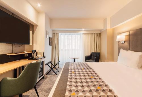 a hotel room with a bed and a flat screen tv at Holiday Inn Bucharest - Times by IHG in Bucharest