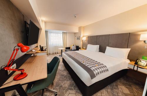 a hotel room with a large bed and a desk at Holiday Inn Bucharest - Times by IHG in Bucharest