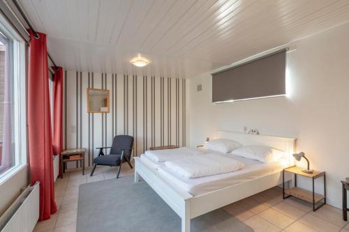 - une chambre avec un lit blanc et une chaise dans l'établissement Duinland 186 Sint Maartenszee, à Sint Maartensvlotbrug