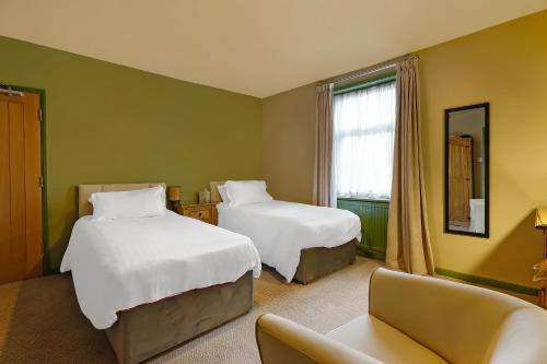 a hotel room with two beds and a couch at OYO The White Horse, Ripon North Yorkshire in Ripon