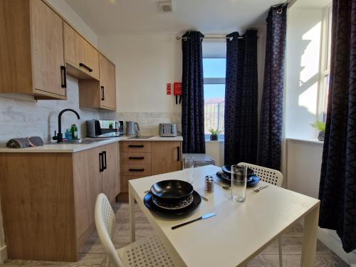 a kitchen with a white table and chairs in a kitchen at Flat 2, Modern Studio apartment, Tynte Hotel, Mountain Ash in Quakers Yard