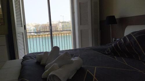 ein Hotelzimmer mit Handtüchern auf einem Bett mit Fenster in der Unterkunft Sea View 2 bedroom apartment in Marsaskala