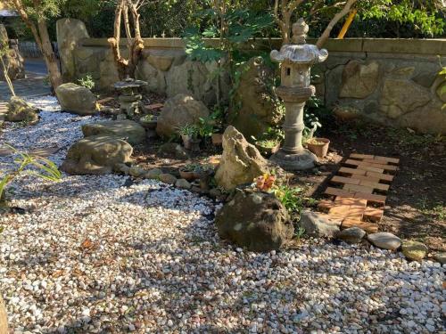 a garden with a fountain and rocks and a stone wall at 貸切海別荘　手ぶらBBQ 海まで徒歩5分ペット可　駐車場5台以上 in Kido