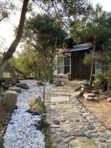 a garden with a stone walkway in front of a house at 貸切海別荘　手ぶらBBQ 海まで徒歩5分ペット可　駐車場5台以上 in Kido