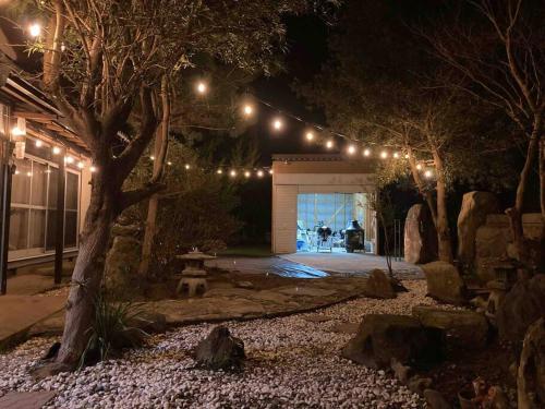 a garden at night with lights on a garage at 貸切海別荘　手ぶらBBQ 海まで徒歩5分ペット可　駐車場5台以上 in Kido