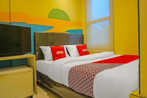 a bedroom with a bed with red pillows and a tv at SUPER OYO 92271 Orienchi 3 in Tangerang