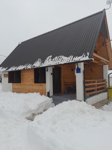 a log cabin with snow on the ground in front of it at Kuća za odmor Antonija in Gospić