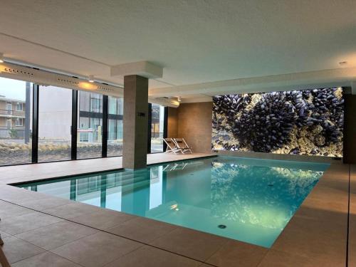 een zwembad in een gebouw met een aquarium bij The Loft - Full Sea View - use of hotels Sauna and Pool in Cadzand