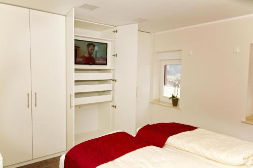 a white bedroom with a red blanket on a bed at Ferienhaus Saar-Traum in Saarburg