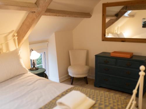 um quarto com uma cama, uma cadeira e um espelho em Pass the Keys Character country cottage with scenic castle views em Llandeilo