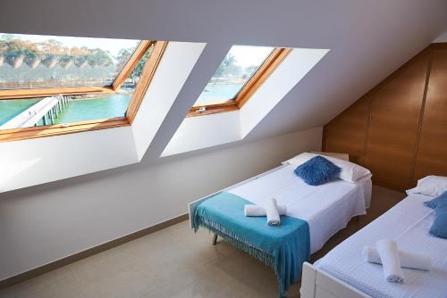 2 Betten in einem Zimmer mit 2 Fenstern in der Unterkunft Exclusivo ático boutique con vistas al mar in Vilanova de Arousa