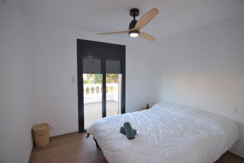 Schlafzimmer mit einem weißen Bett und einem Deckenventilator in der Unterkunft 399-Casa moderna con amarre 14m y piscina privada in Empuriabrava