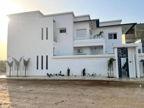 ein weißes Haus mit Palmen davor in der Unterkunft Diamond House in Saly Portudal
