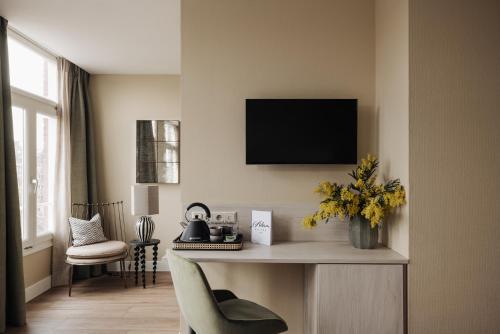 a living room with a desk with a tv on the wall at Adam Suites Hotel in Amsterdam