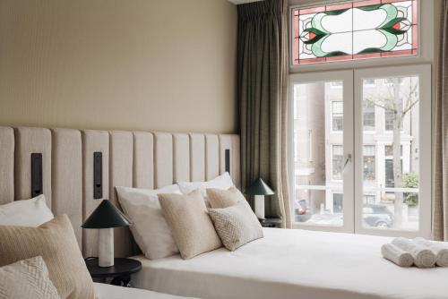 a bedroom with a large white bed with a window at Adam Suites Hotel in Amsterdam