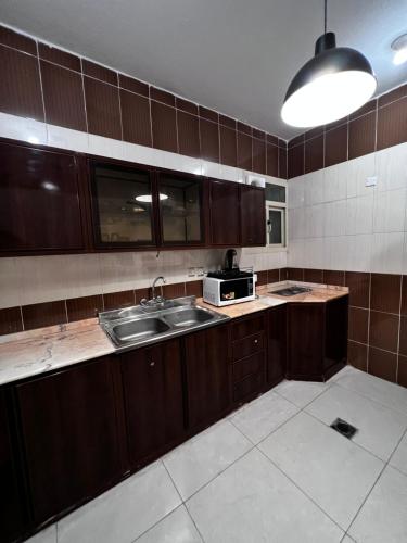 a kitchen with a sink and a microwave at أجنحة ورد للشقق المخدومة in Khamis Mushayt