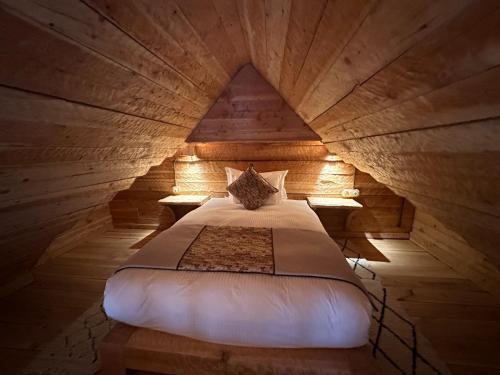 a bedroom with a bed in a wooden room at Hotel Xaluca Spa Aguelmame Sidi Ali in Aguelman