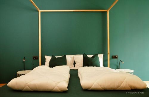 1 cama con almohadas blancas y pared verde en Foresteria Cà di Nadin, en Carriola