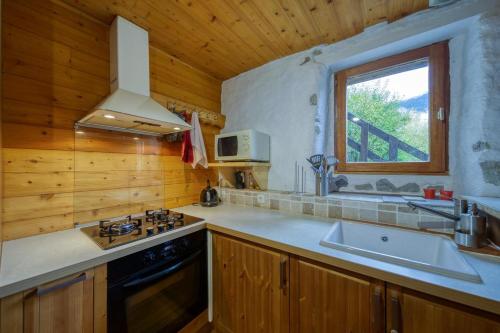 une cuisine avec évier et cuisinière ainsi qu'une fenêtre dans l'établissement Chalet View on Vanoise Mountain - 3 bedrooms 70m2, à Cevins