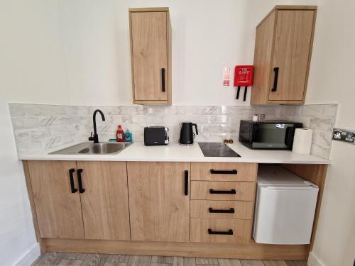 a kitchen with a sink and a microwave at Flat 3. Modern one bed apartment, Tynte Hotel, Mountain Ash in Quakers Yard