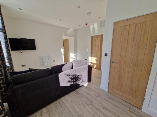 a living room with a couch and a wooden door at Flat 3. Modern one bed apartment, Tynte Hotel, Mountain Ash in Quakers Yard
