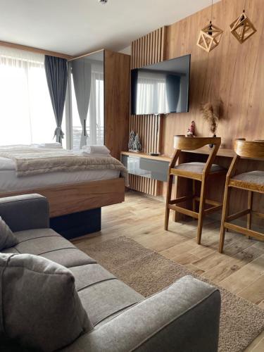a hotel room with a bed and a table and a couch at Apartmani NLUX and SPA in Kopaonik