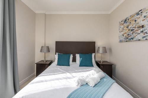 ein Schlafzimmer mit einem großen Bett mit blauen Kissen in der Unterkunft RAD STAYS - 60 Westpoint 89 Grayston Dr Morningside in Johannesburg