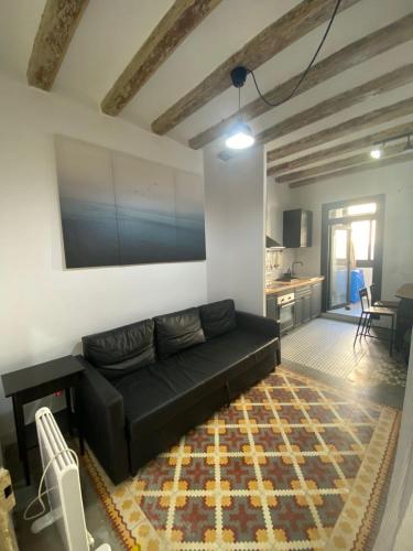 ein Wohnzimmer mit einem schwarzen Sofa und einer Küche in der Unterkunft Spacious Modern Apartment in the Vibrant El Raval in Barcelona