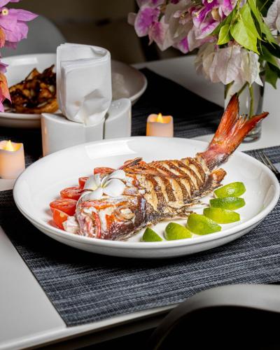 a plate of fish and vegetables on a table with candles at Ahiva Village in Fulhadhoo